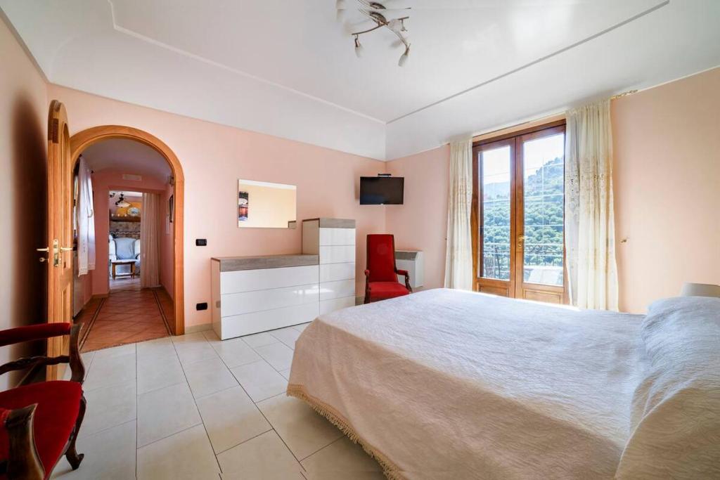a bedroom with a bed and a desk and a window at Casa vacanze Civale con Jacuzzi e parcheggio in Ravello