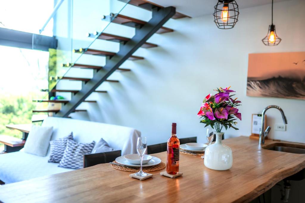 Tropical Loft Home - Ocean View في سان خوان ديل سور: طاولة خشبية عليها زجاجة من النبيذ والزهور