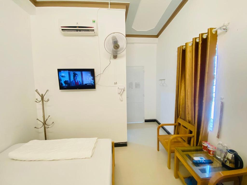 Cette chambre comprend un lit, une table et un ventilateur. dans l'établissement Hotel Aloha 2, à Ninh Hải