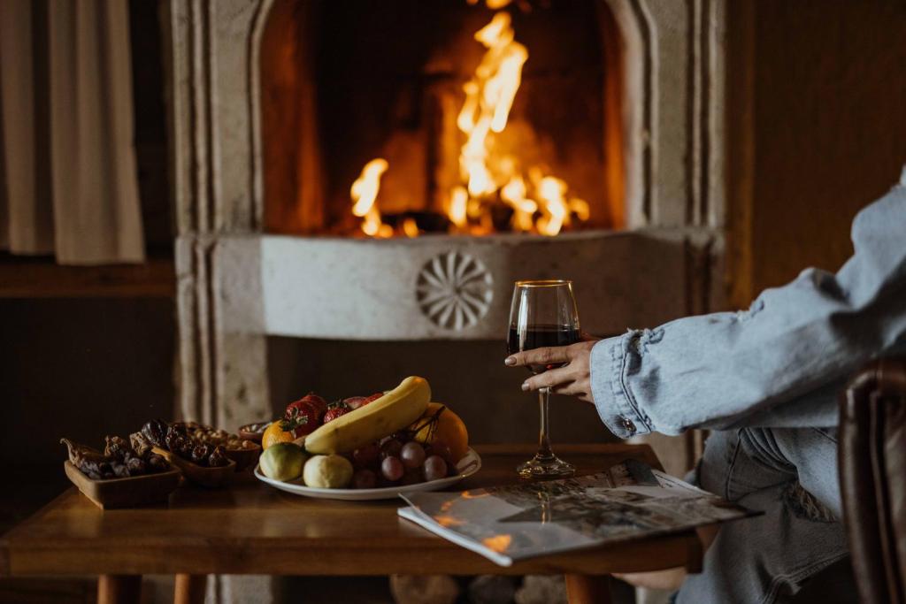 eine Person, die vor einem Kamin ein Glas Wein hält in der Unterkunft Seki Cave Suites in Goreme