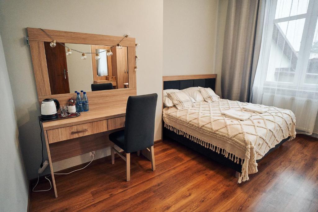 a bedroom with a bed and a desk with a mirror at Hotel Lilia in Włoszczowa