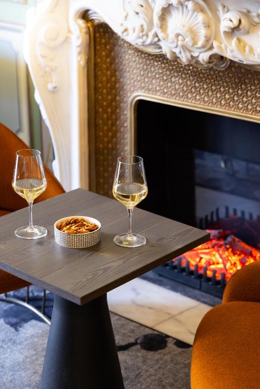 two glasses of wine on a table in front of a fireplace at Hôtel Vendôme in Nice