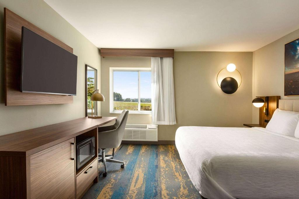 コロンビアにあるLa Quinta Inn by Wyndham Columbia NE Fort Jacksonのベッドと机とテレビがあるホテルの部屋