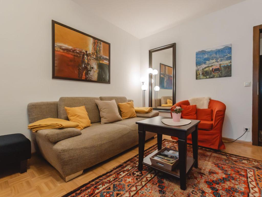 ein Wohnzimmer mit einem Sofa und einem orangenen Stuhl in der Unterkunft Apartment Orlic by Interhome in Bad Hofgastein