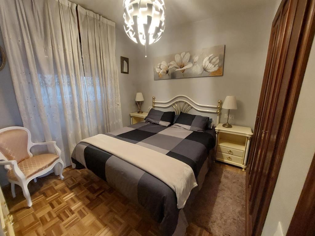 a bedroom with a black and white bed and a chandelier at apartamento central in Ribadesella
