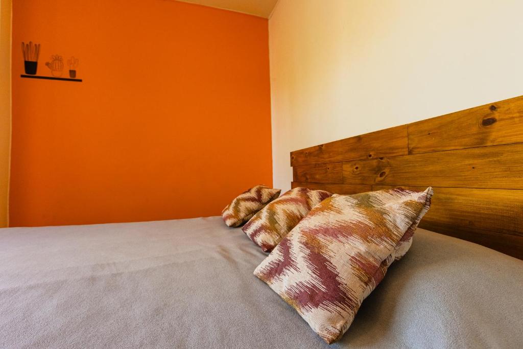 Un dormitorio con una cama con una pared naranja. en Céntrico Departamento Tangerine San Rafael, en San Rafael