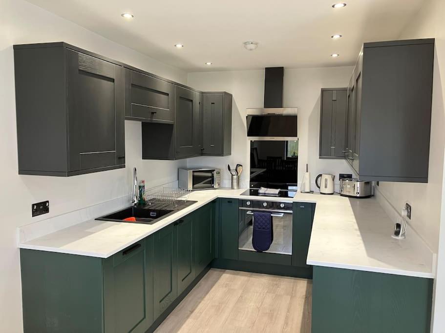 a kitchen with green cabinets and white counter tops at Newly renovated, modern bungalow - quiet location in Lytham St Annes