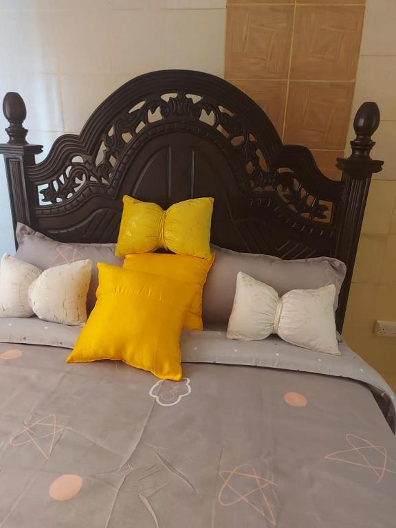 a bed with yellow and white pillows on it at Mrembo Lovely Nest in Nairobi