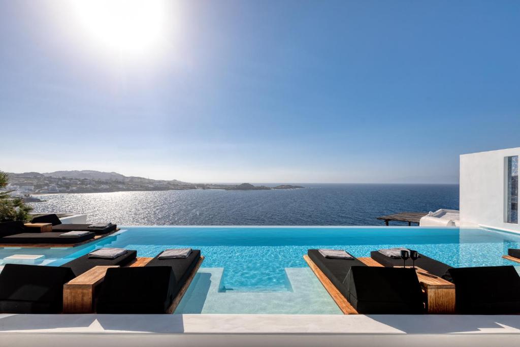 a swimming pool with a view of the ocean at Psarou Black Villas in Mikonos