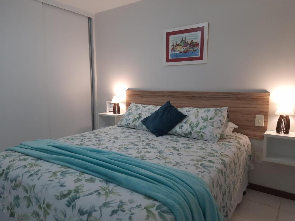 a bedroom with a bed with a blue blanket on it at Loft tropical na praia de Vilas do Atlântico in Lauro de Freitas