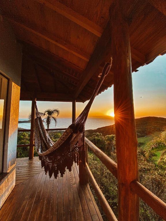 a hammock on a porch with a view of the ocean at Casa do Morro in Praia do Rosa
