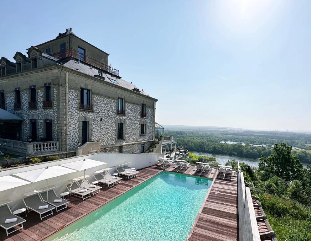 a hotel with a swimming pool and chairs and a building at Domaine De La Corniche in Rolleboise