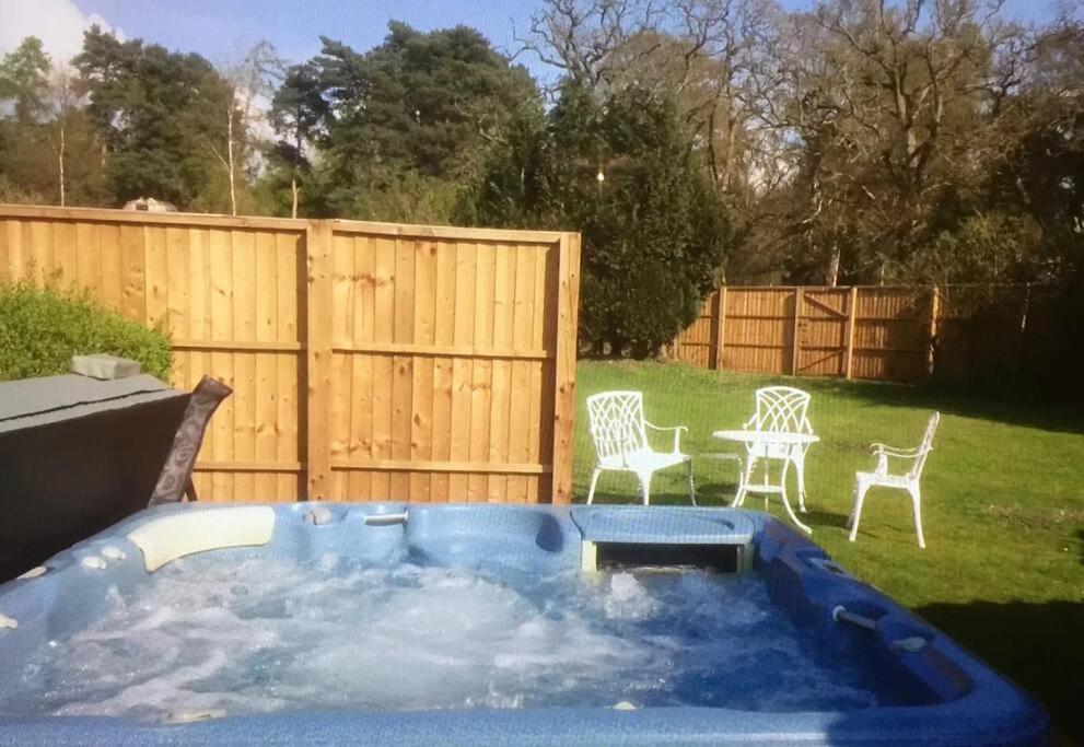 een hot tub in de tuin met stoelen en een hek bij Cosy Countryside Cottage - Hot Tub & Dog friendly in Castle Rising