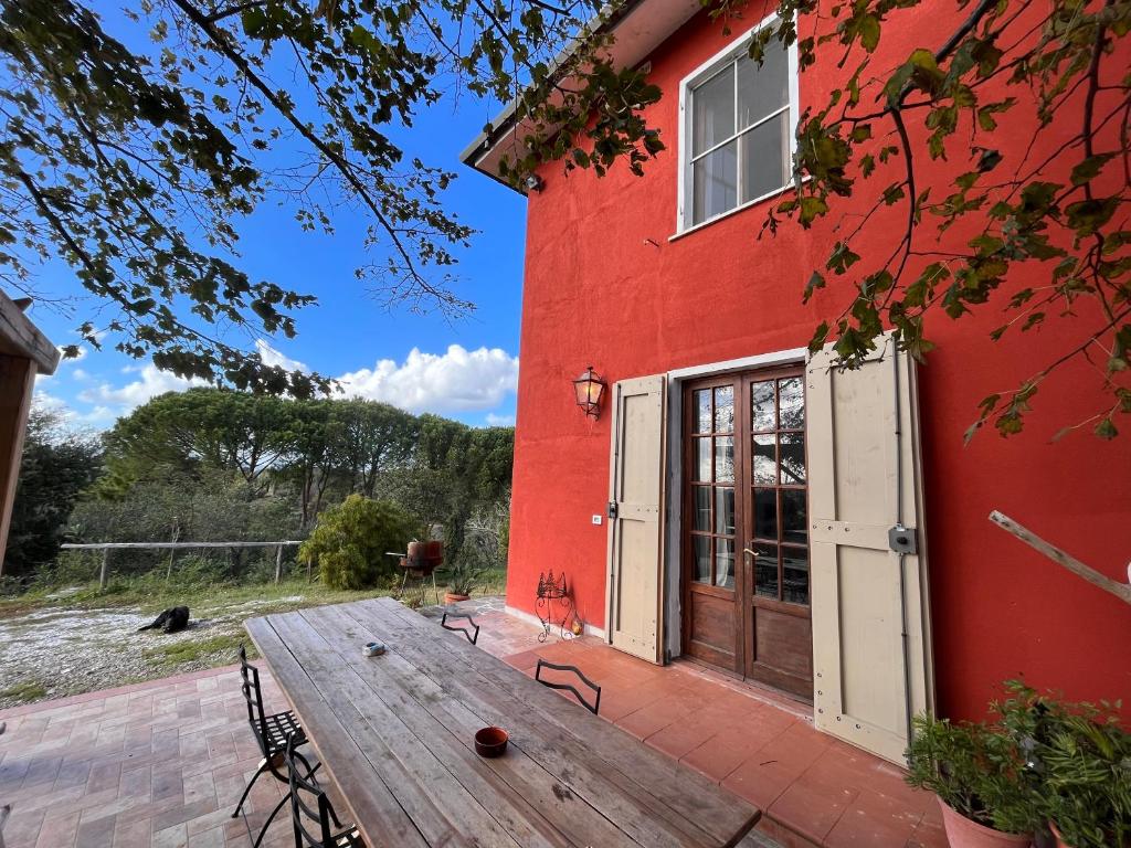un edificio rojo con una mesa de madera delante de él en Podere Orzale Agri b&b, en Usigliano