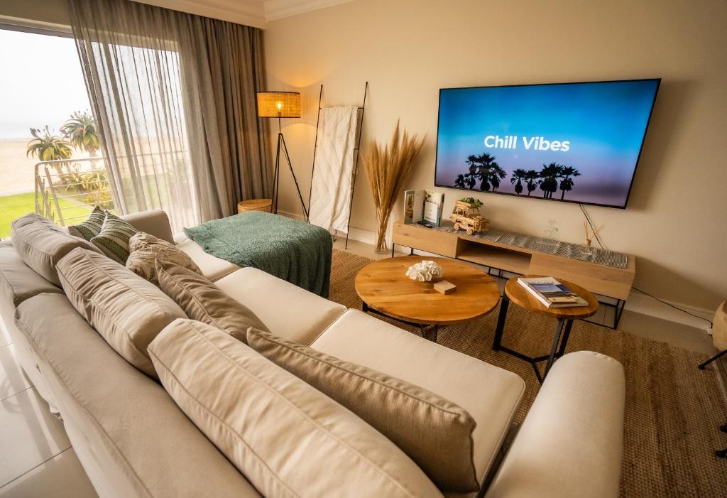 ein Wohnzimmer mit einem Sofa und einem Flachbild-TV in der Unterkunft Deja Blue Beachfront Villa, Newly renovated in Langstrand