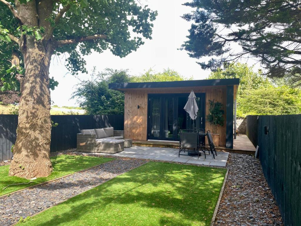 1 bedroom rural cabin retreat with hot tub in Hambrook close to Bristol city centre في بريستول: سقيفة صغيرة مع شجرة في الفناء