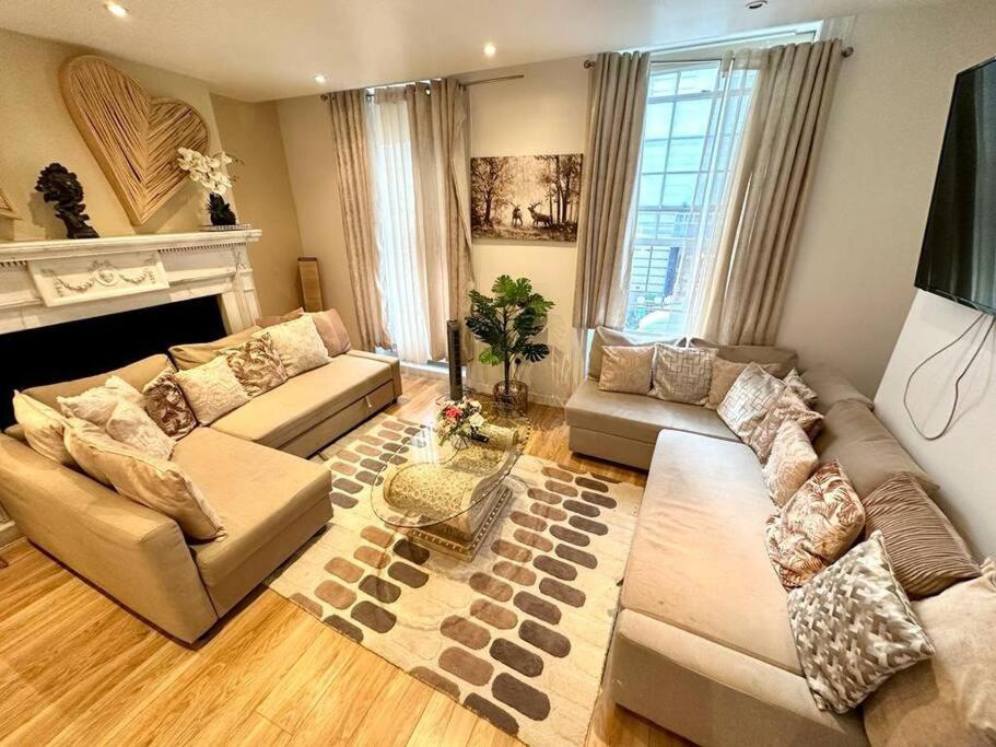 a living room with two couches and a fireplace at H1: Stunning Large Apt - Under 100m to Piccadilly Circus! in London