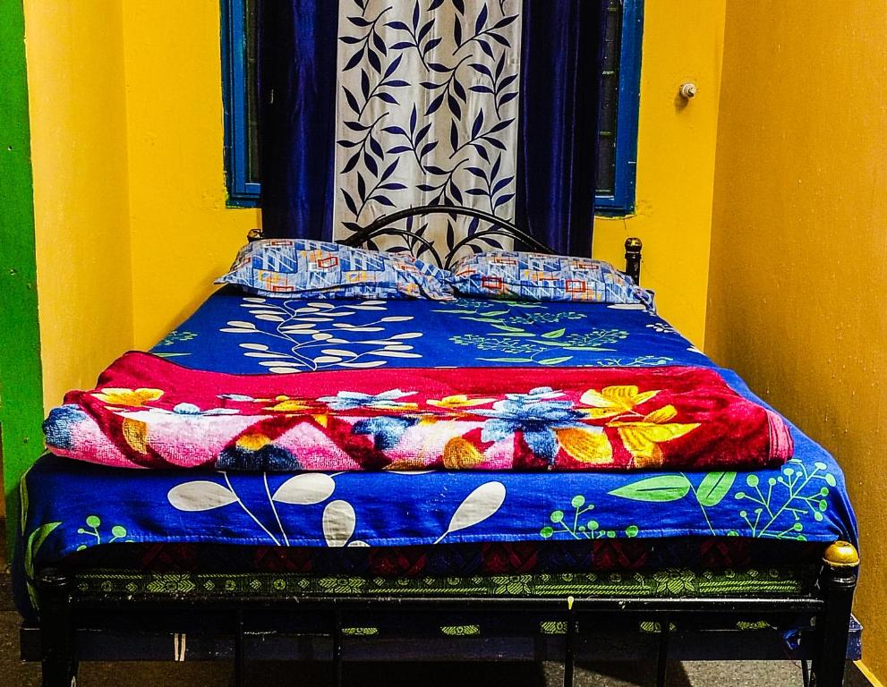 a bed with a colorful blanket and pillows on it at Saibaba Homestay in Kanchipuram