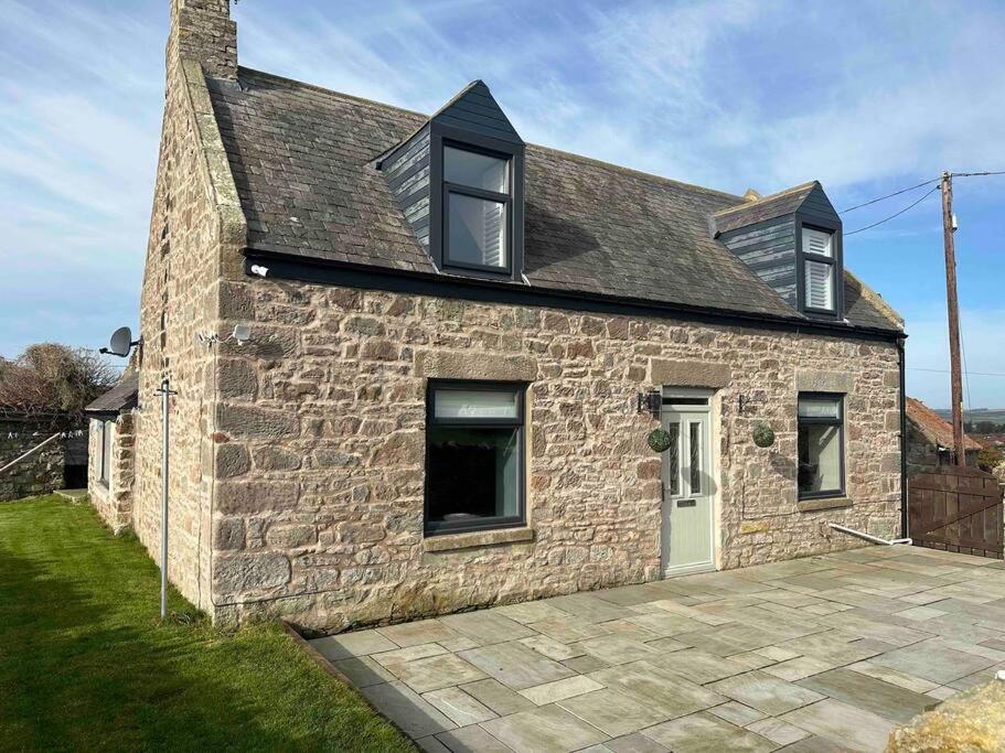 a stone house with a white door and windows at Prior House Farm in Berwick-Upon-Tweed