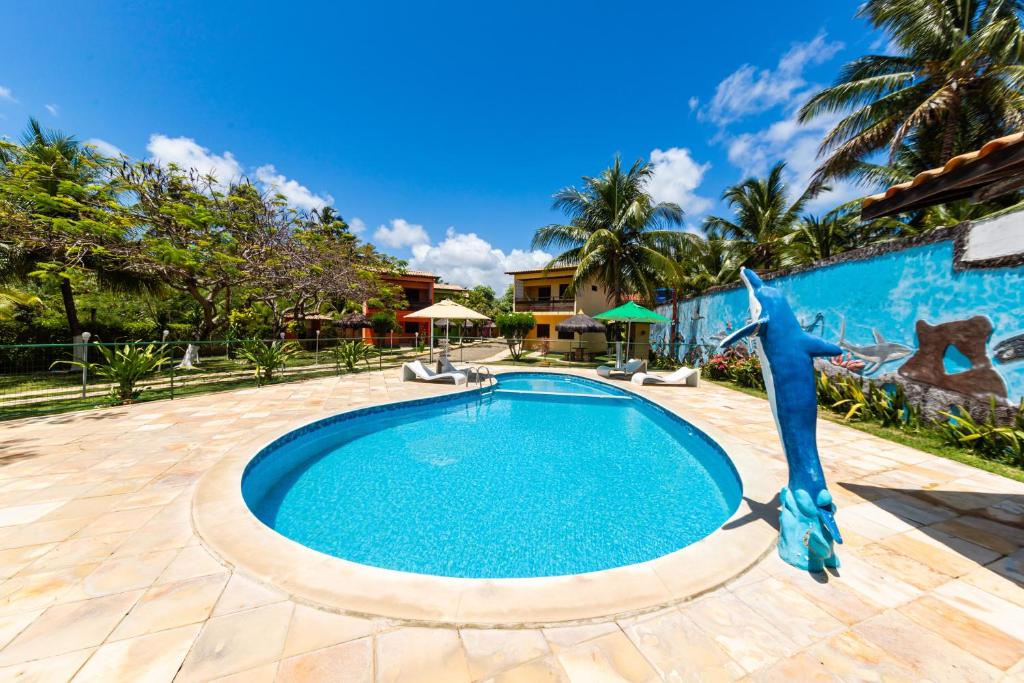 uma piscina com uma estátua de golfinho ao lado de uma casa em Residencial Maragogi em Maragogi