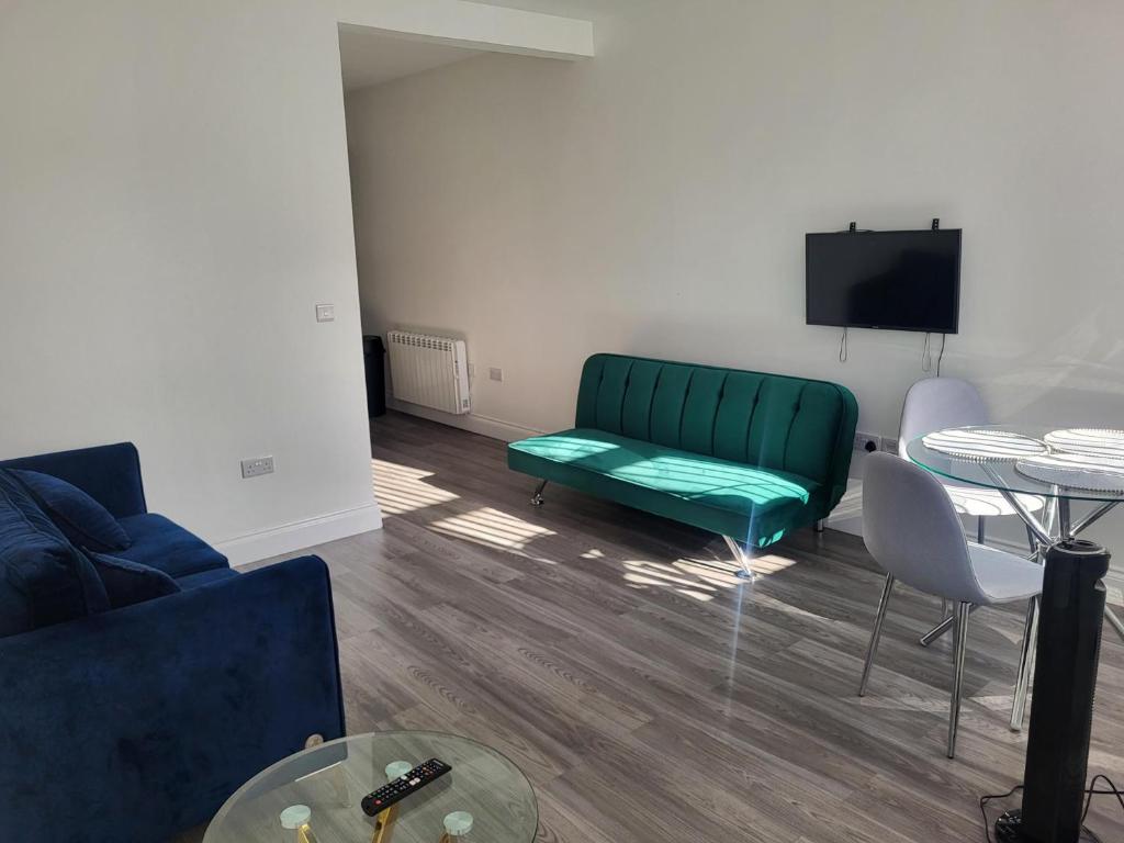 a living room with a green couch and a table at NEW 1 BED FLAT IN DARTFORD- 40 Mins into London -SLEEPS 3-FIBRE BROADBAND-PARKING-10 MINS WALK TO CITY CENTRE in Kent