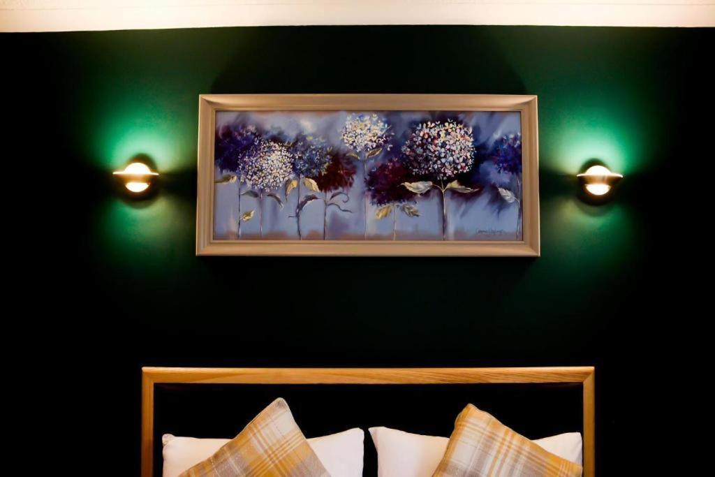 una pintura de flores en una pared verde con luces en Lomond Park Hotel, en Balloch