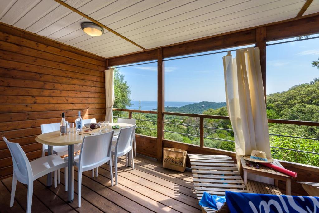 a dining room with a table and chairs on a wooden deck at Camping U Pirellu in Porto-Vecchio