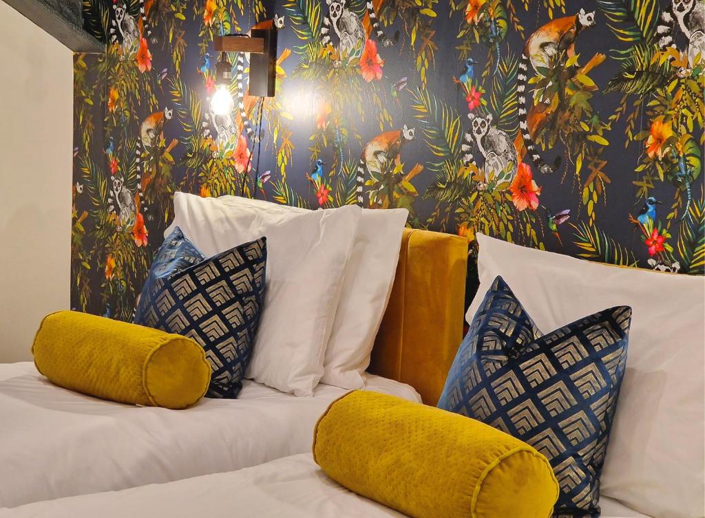 1 cama con almohadas amarillas y papel pintado con motivos florales en The Academy House by Bevolve, en Shrewsbury