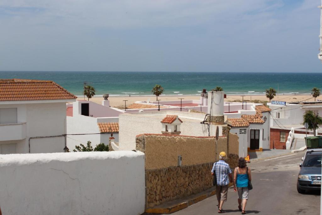 dos personas caminando por una calle junto a una playa en Apartamentos Muro, Juana & Charca, en Conil de la Frontera