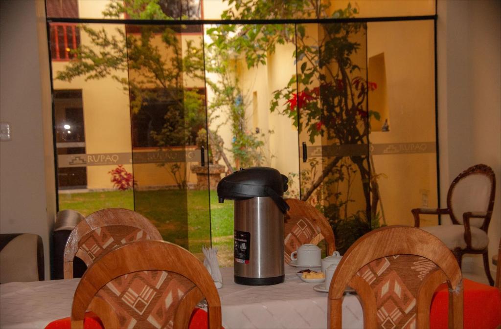 una mesa con sillas y una cafetera. en Inka's Haven Hotel en Ollantaytambo