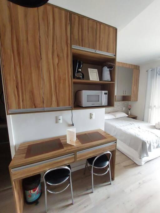 a bedroom with a bed and a desk with two chairs at Studio próximo ao Metrô Belém. in São Paulo
