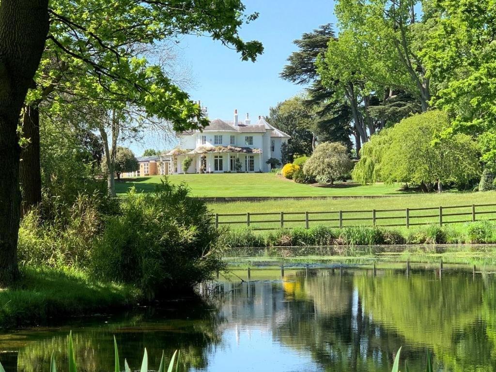 una casa con un estanque delante de ella en Denham Mount en Buckinghamshire