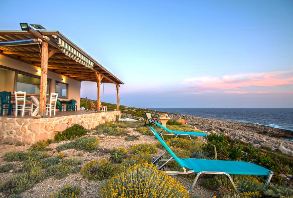 ein Strandhaus mit Liegestühlen und dem Meer in der Unterkunft White Rock Cave Villa in Kampíon