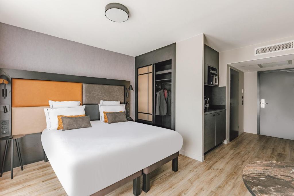 une chambre avec un grand lit blanc dans une pièce dans l'établissement Appart'City Collection Paris Gare de Lyon, à Paris