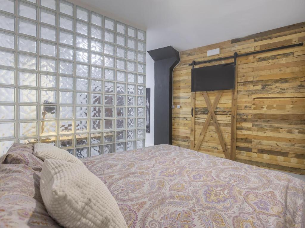 une chambre avec un lit et un mur en bois dans l'établissement LU&CIA Calle Manrique, à Malaga