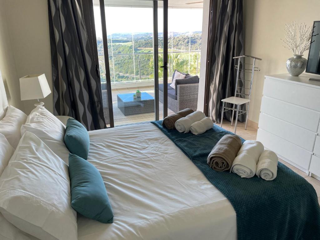 1 cama blanca grande con toallas y almohadas. en Superior apartment for golf, sea and nature lovers, en Casares