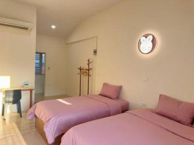 two beds in a room with pink sheets at NooN23 Hostel in Chiang Mai