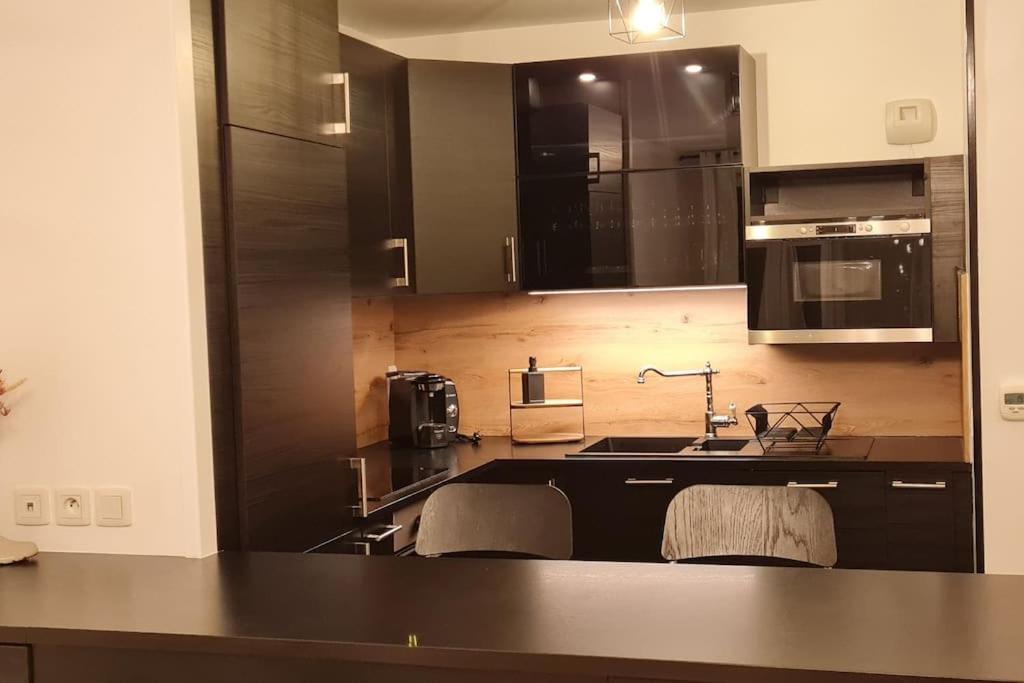 uma cozinha com armários pretos e um lavatório em Mon petit chez-toi Appart proche Parc des Expositions Aéroport CDG em Aulnay-sous-Bois