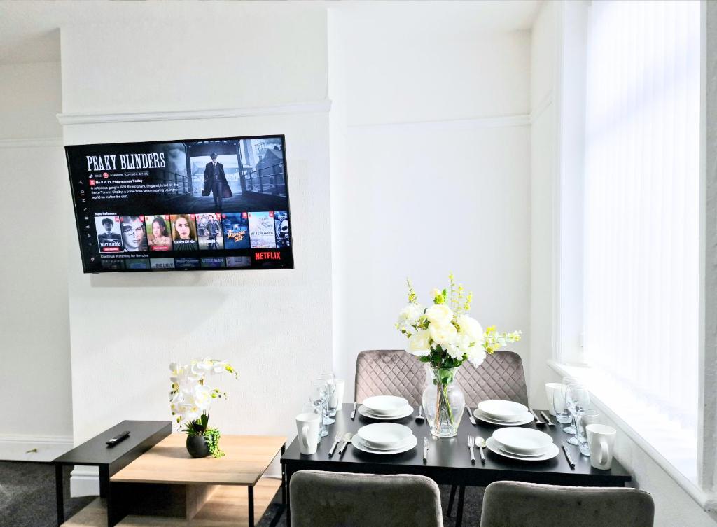 a dining room with a table and a tv on the wall at Burnley Terraced House by BEVOLVE - Free Parking 3 in Burnley