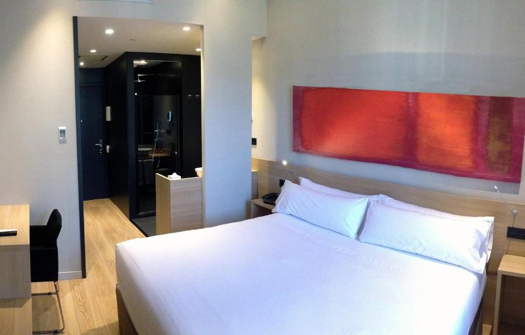 バルセロナにあるホテル アンビット バルセロナの白いベッドと壁に絵画が飾られたベッドルーム1室