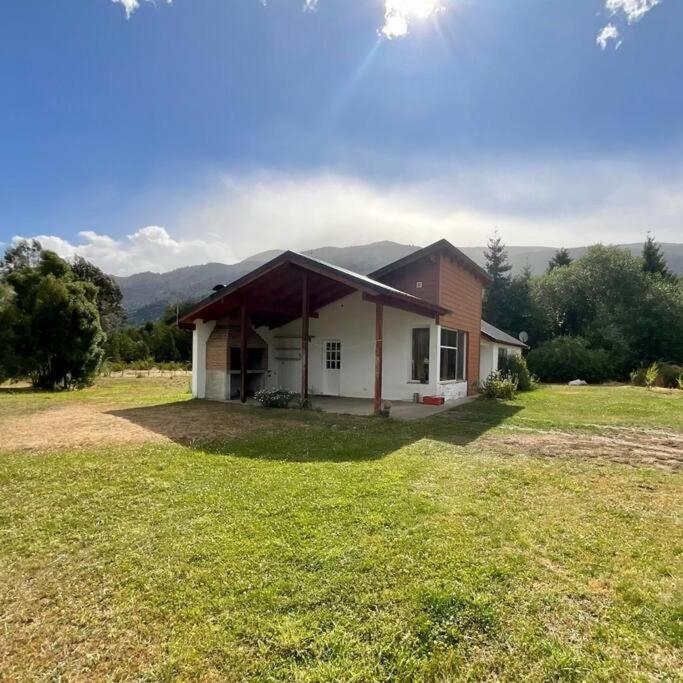 een klein huis in een veld met een grasveld bij Casa Nehuen in Lago Puelo