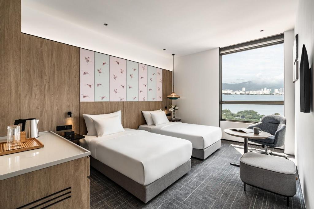ein Hotelzimmer mit 2 Betten und einem Schreibtisch in der Unterkunft Crowne Plaza Penang Straits City, an IHG Hotel in Perai
