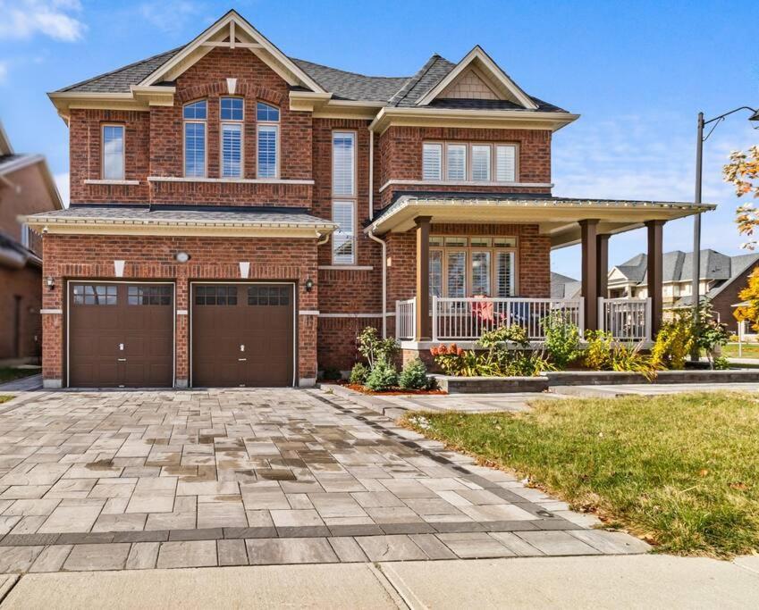 a brick house with two garage doors in a driveway at Ski getaway - 10 min to Snow Valley/ BBQ/ Backyard in Barrie