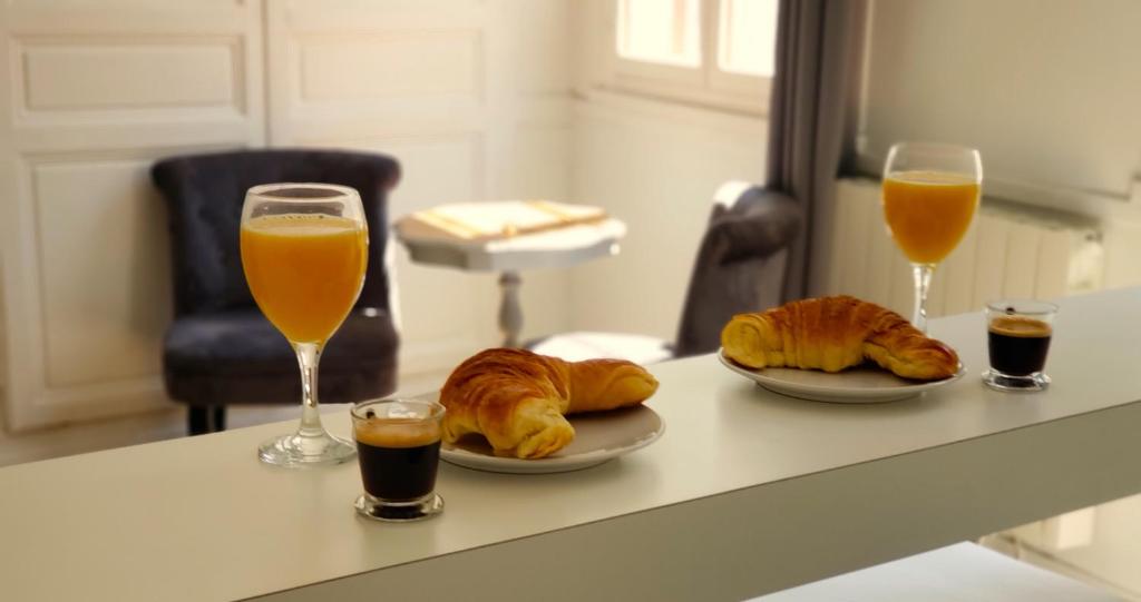 魯昂的住宿－Appart Rouen Centre，桌子上放着两杯橙汁和羊角面包