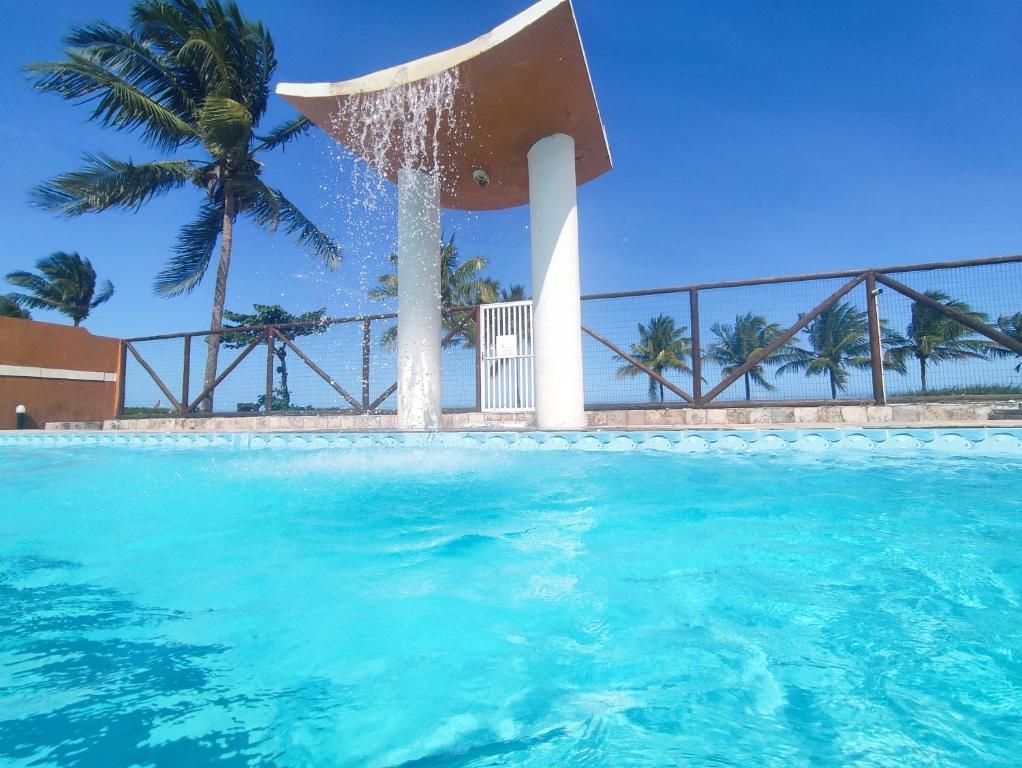 a swimming pool with a fountain in the water at APARTAMENTO 104- BGMC in Guaibim