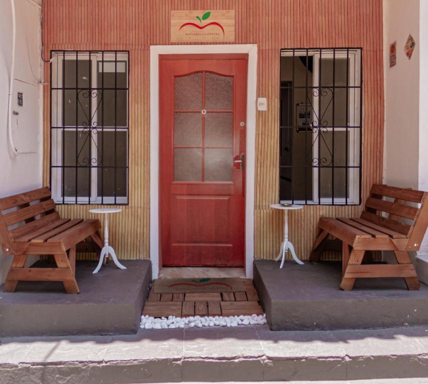 two benches sitting in front of a red door at Matianellu Hostel in Rio de Janeiro