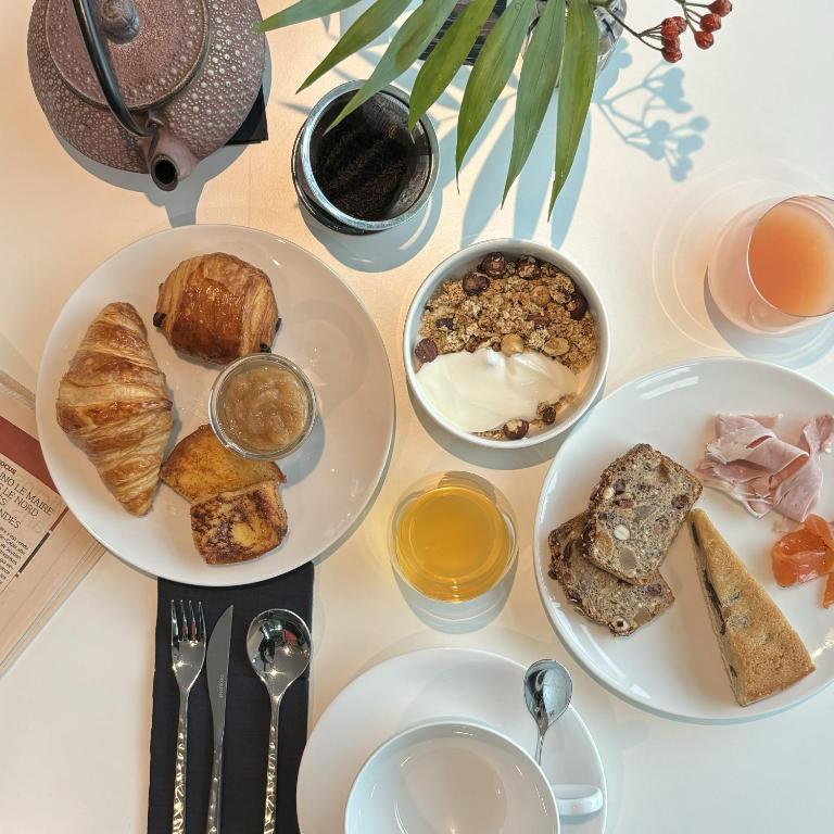 a table topped with plates of food and bowls of bread at L'Agapa Hôtel - Spa Codage in Perros-Guirec