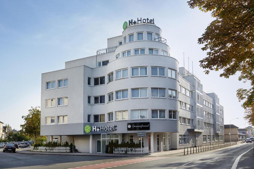 un edificio blanco con un cartel encima en H+ Hotel Darmstadt, en Darmstadt