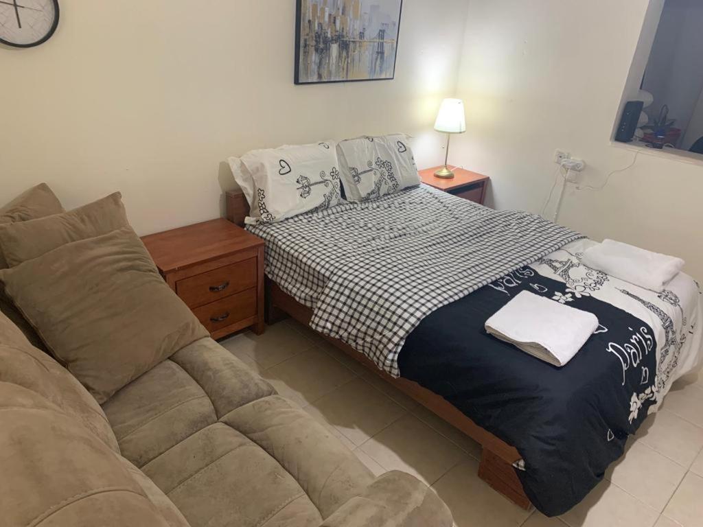 a bedroom with a bed next to a couch at משמר הגבול 9 דירה 4 in Haifa