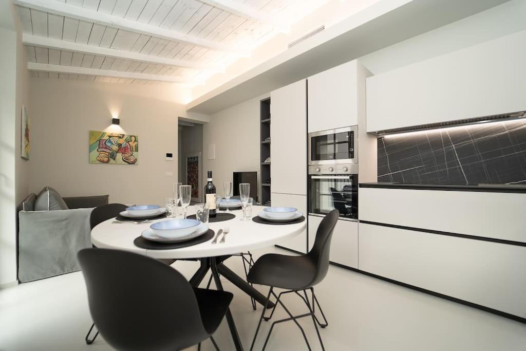 科莫的住宿－Appartamento moderno a 2 minuti dal duomo di Como，厨房以及带白色桌椅的用餐室。